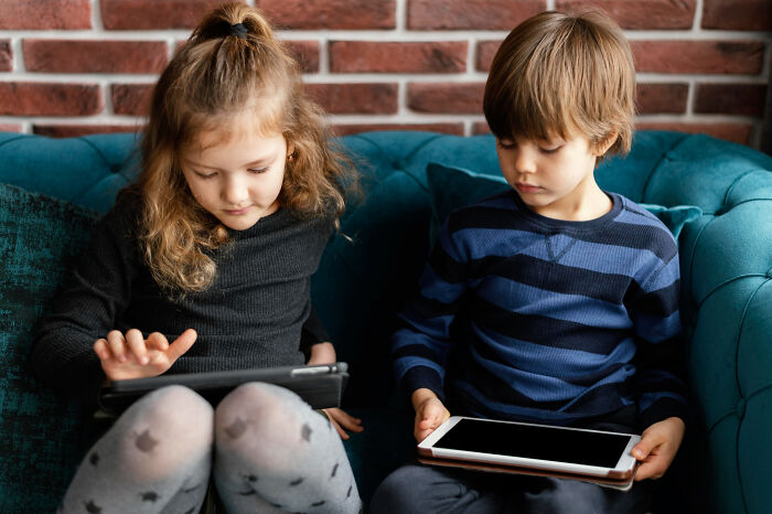 Two young kids focused on their tablets, showing behaviors of concentration and focus.