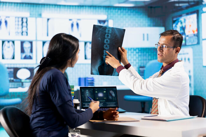 A doctor pointing to an X-ray during a medical consultation to read diagnostic behaviors.
