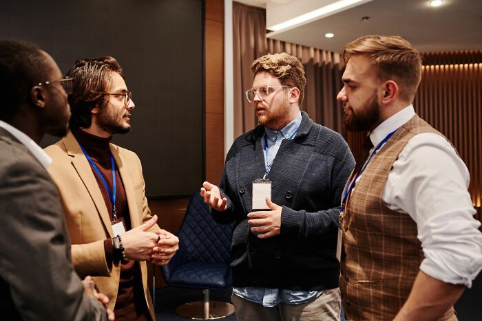 Four business professionals talking in a group, demonstrating body language and how people read behaviors.