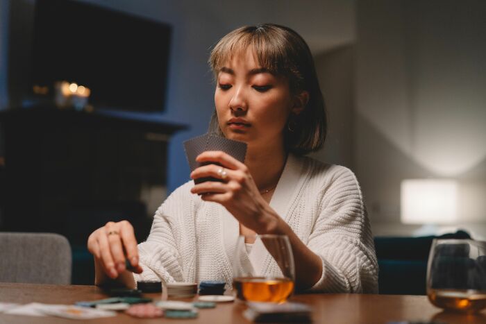 A focused woman playing cards and analyzing her hand, showcasing how professionals read people and behaviors.