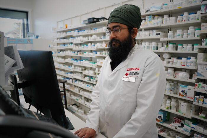 A pharmacist at a computer analyzing prescriptions, demonstrating focused professional behaviors.