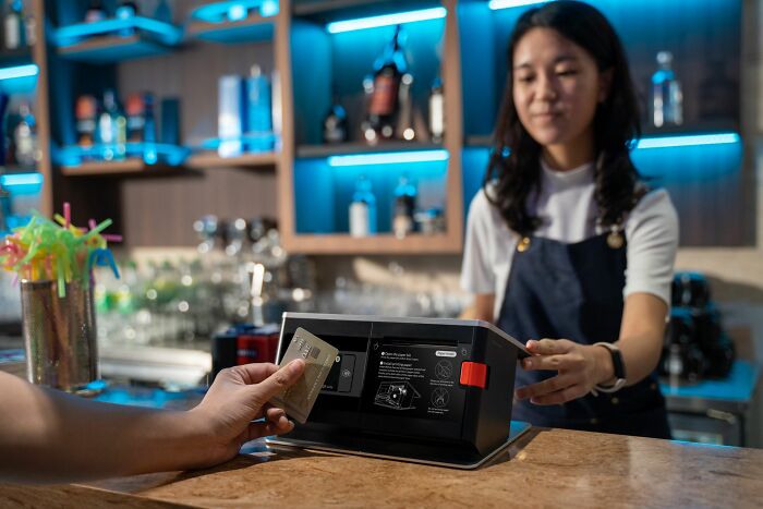 A cashier accepting a card payment at a bar, exhibiting attentive service behaviors.