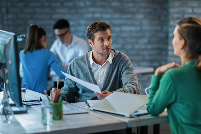An office meeting where professionals read people by discussing a document together.