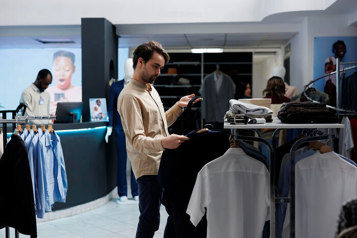A shopper displaying thoughtful consumer behaviors while browsing clothes