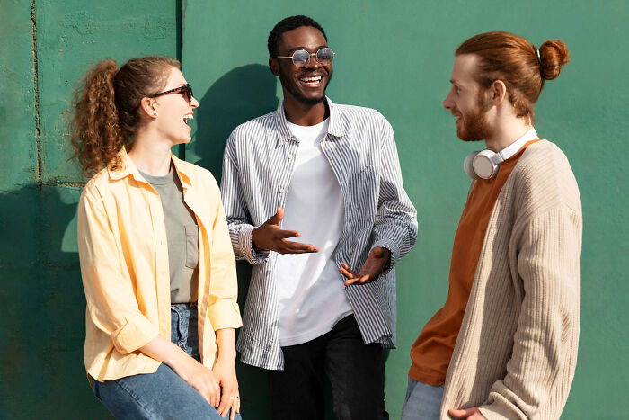 Three young friends laughing together and showing positive social behaviors outdoors