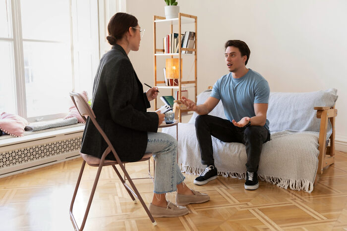 A therapist taking notes as a man expresses himself, highlighting communicative behaviors