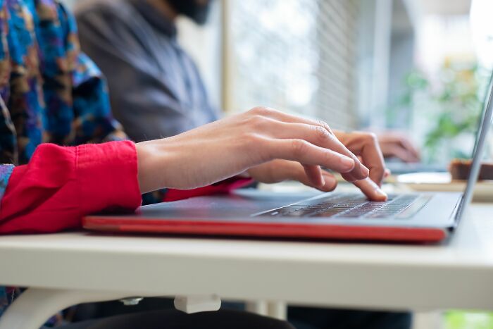 Close-up of hands typing on laptop keyboard in a casual setting