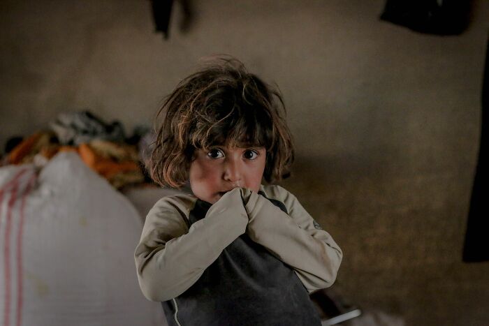Young child looking shy in dim light illustrating innocent secrets