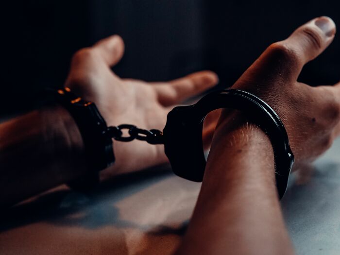 Hands in handcuffs on a table symbolizing secrets and consequences