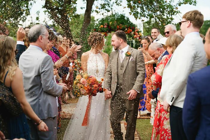 Bride and groom walking through guests throwing confetti at wedding ceremony