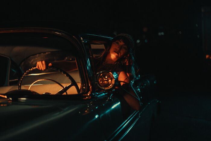 Woman in vintage car at night representing hidden secrets