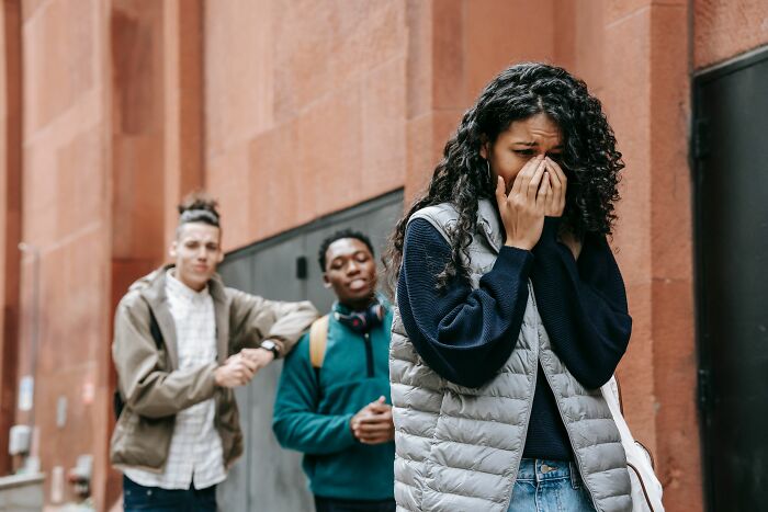 Young woman upset while two people talk behind her outdoors