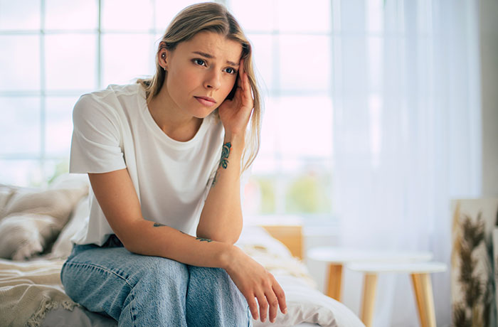 A woman looking distressed on a bed, contemplating her friend's suggestion about a hot GF and weight-loss coach. A woman looking distressed on a bed, contemplating her friend's suggestion about a hot GF and weight-loss coach.