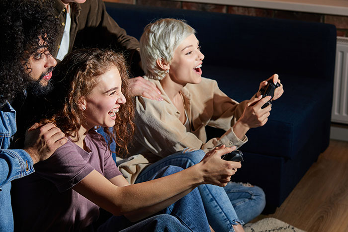A group of friends laughing while playing video games, representing the friendship dynamics around the hot GF and weight-loss coach topic. A group of friends laughing while playing video games, representing the friendship dynamics around the hot GF and weight-loss coach topic.