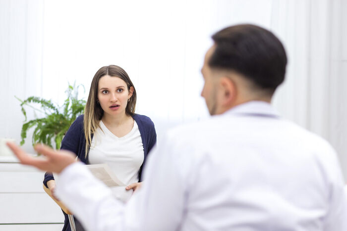 Woman showing surprised reaction to doctor in sexist treatment discussion