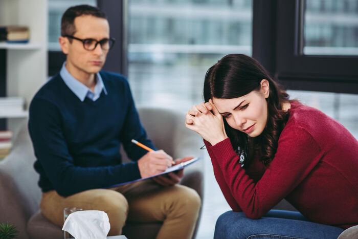 Woman distressed during therapy session showing impact of sexist treatment in healthcare