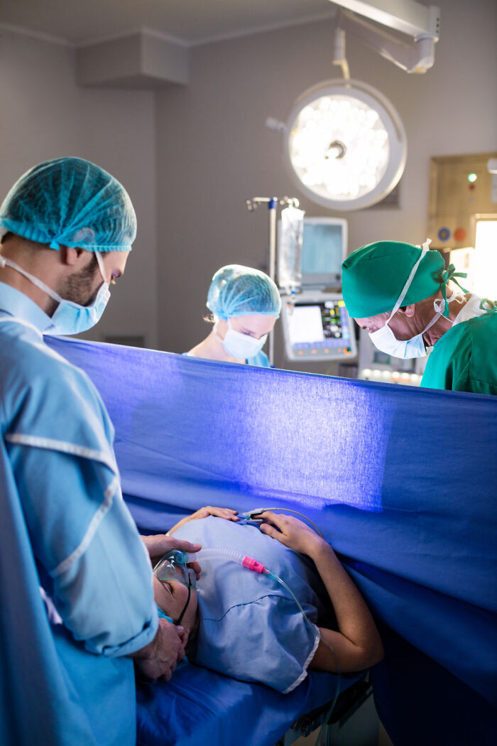 Doctors performing surgery on patient in operating room with medical equipment