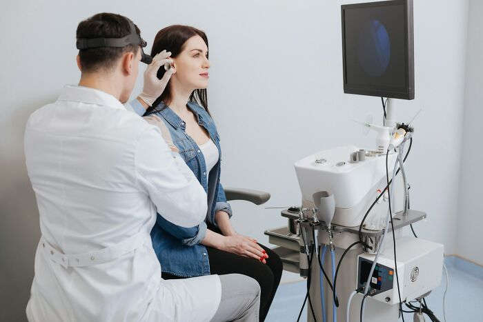 Doctor performing ear examination on female patient about sexist treatment