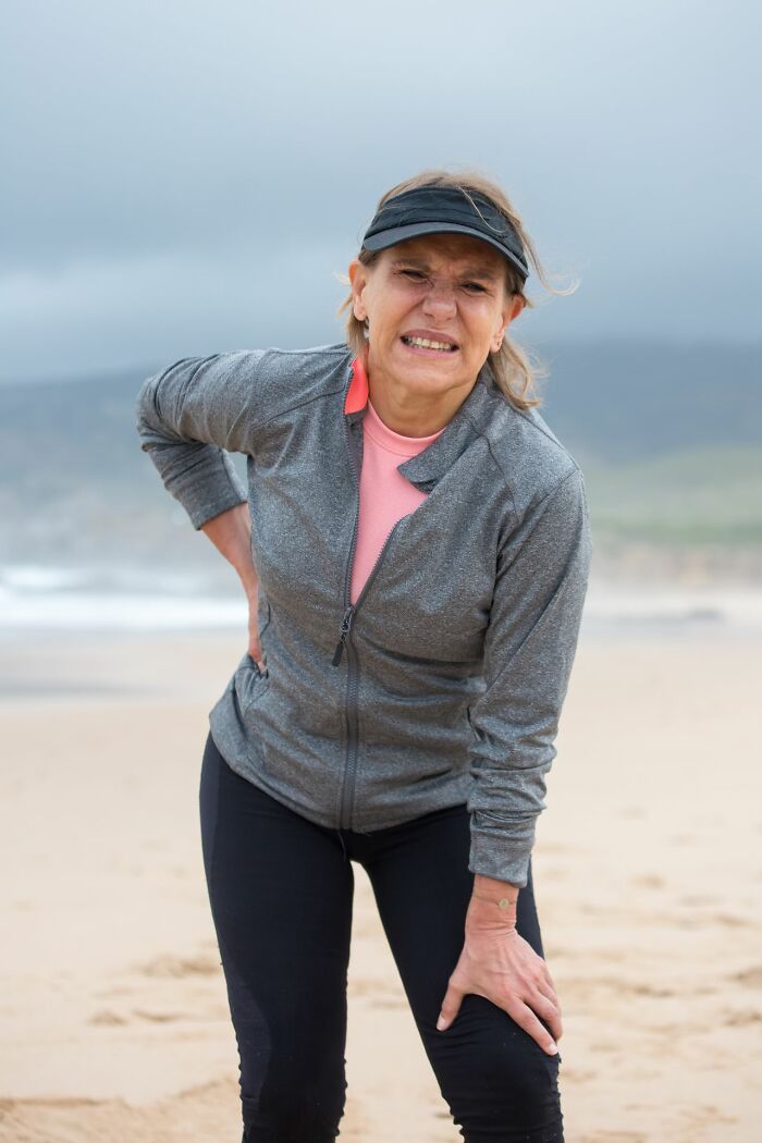 Woman grimacing in pain during outdoor exercise for sexist treatment awareness