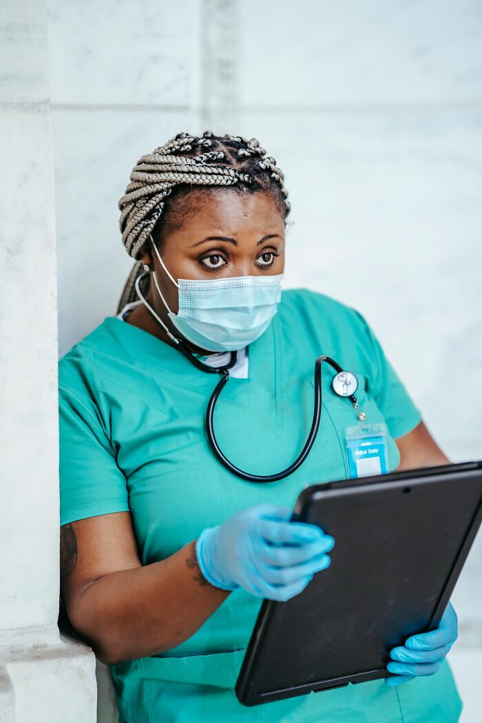 Female doctor reviewing chart wearing surgical mask representing sexist treatment in healthcare