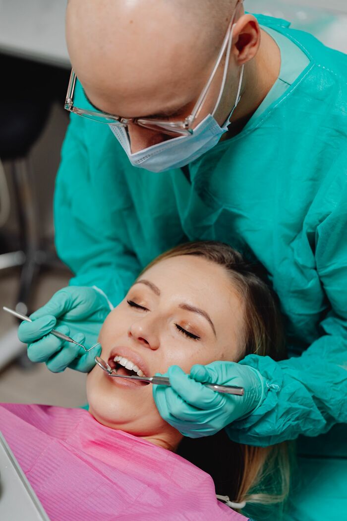 Dentist examining woman's teeth wearing mask highlighting sexist treatment in healthcare