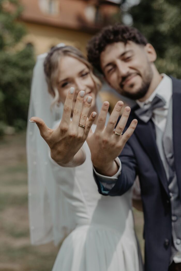 Newlywed couple showing wedding rings outdoors