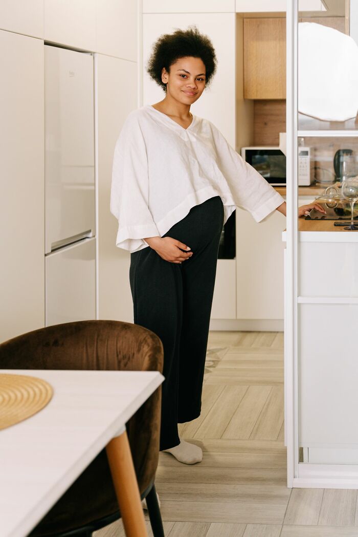 Pregnant woman standing in kitchen holding baby bump