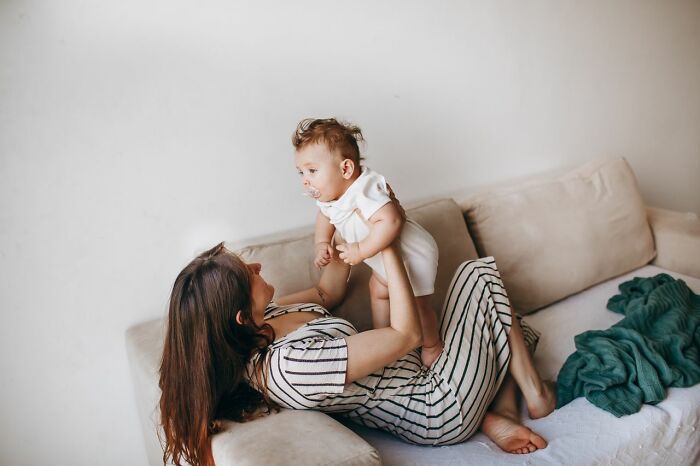 Mother playing with baby on couch highlighting women's health issues