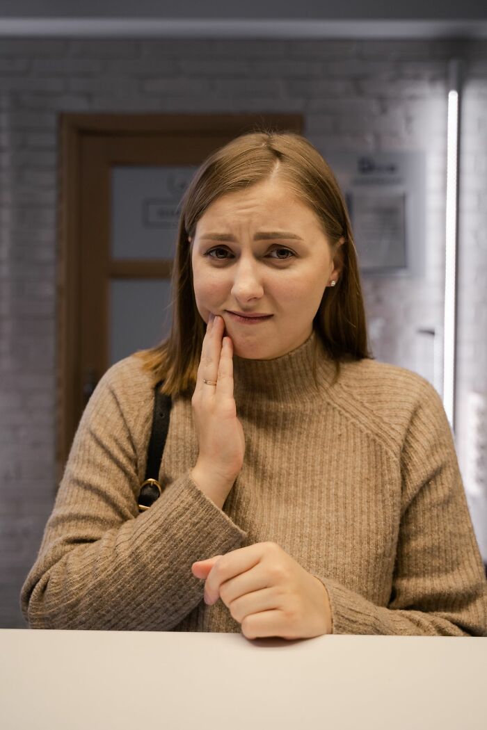 Woman holding jaw in pain depicting sexist treatment in medical care
