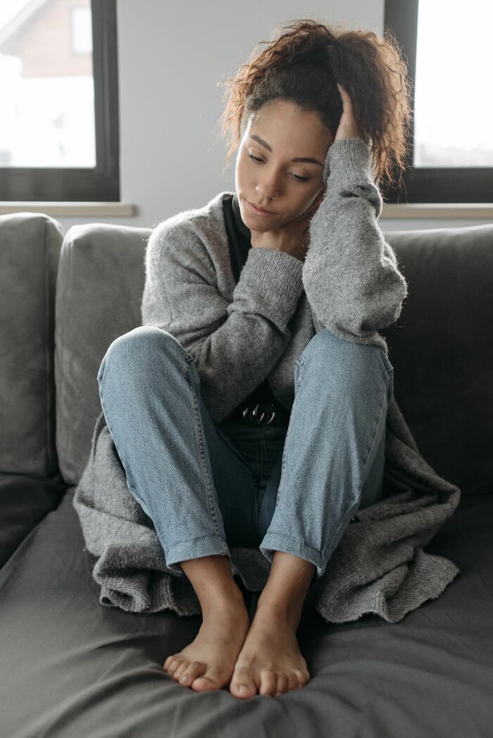 Woman sitting on couch looking sad and stressed