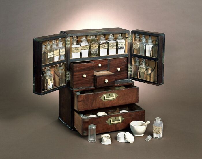 A wooden medicine chest from medical history, filled with various glass apothecary bottles.