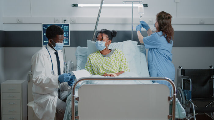 Medical professionals tending to a patient in a hospital bed, highlighting extreme illness and sickness.