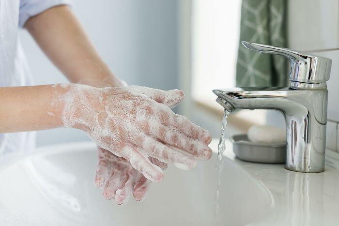 Close-up of hands washing with soap foam by sink