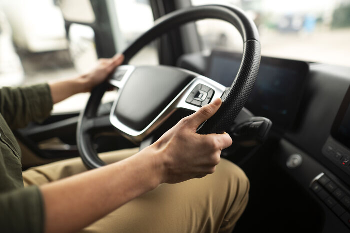 A person's hands on a steering wheel inside a vehicle, connecting to childhood beliefs about driving.