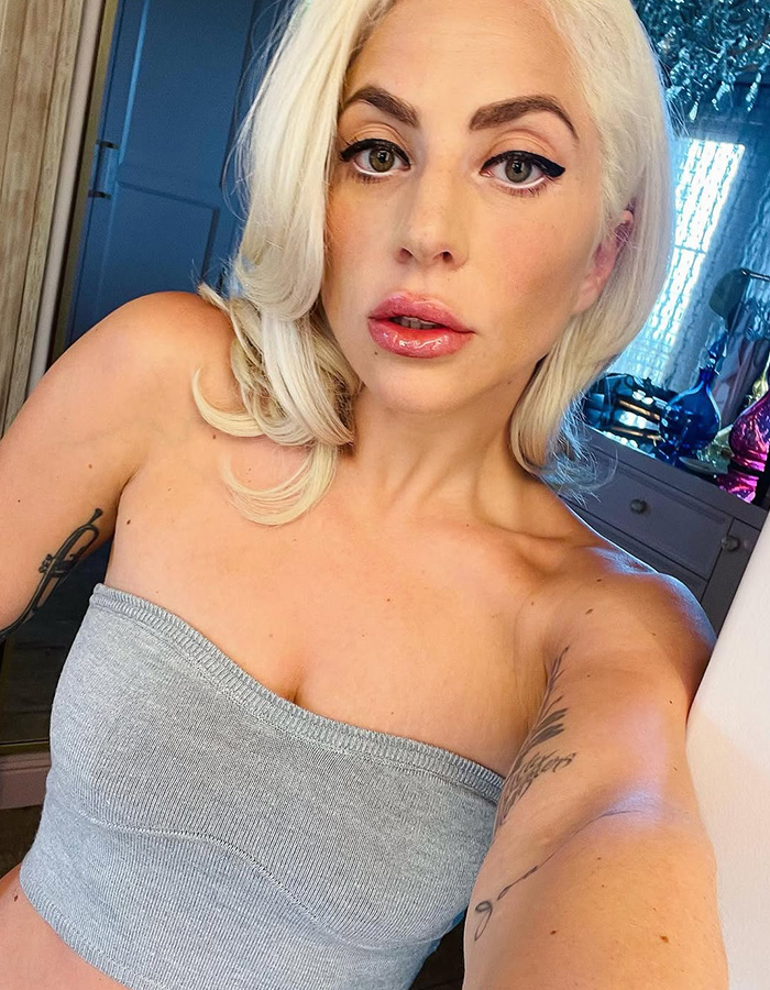 Lady Gaga expecting first baby. She wears a grey tube top, looking into the camera.