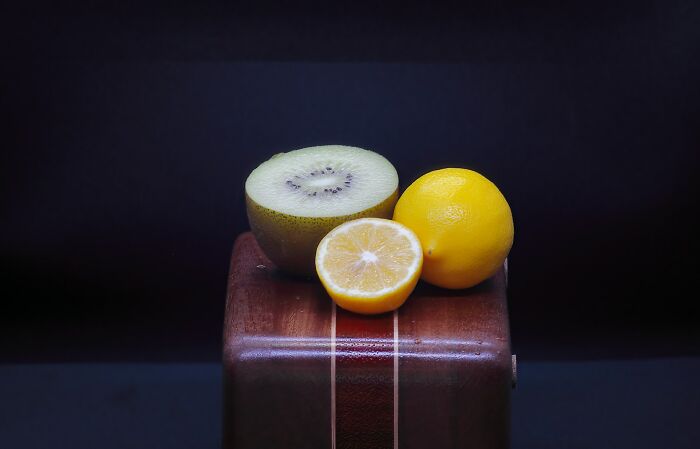 A kiwi fruit, a whole lemon, and a half lemon on a wooden box, showing how stupid things people said.