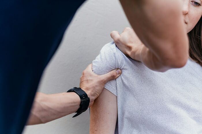 A physical therapist holding a patient's shoulder, showcasing historical medical practices