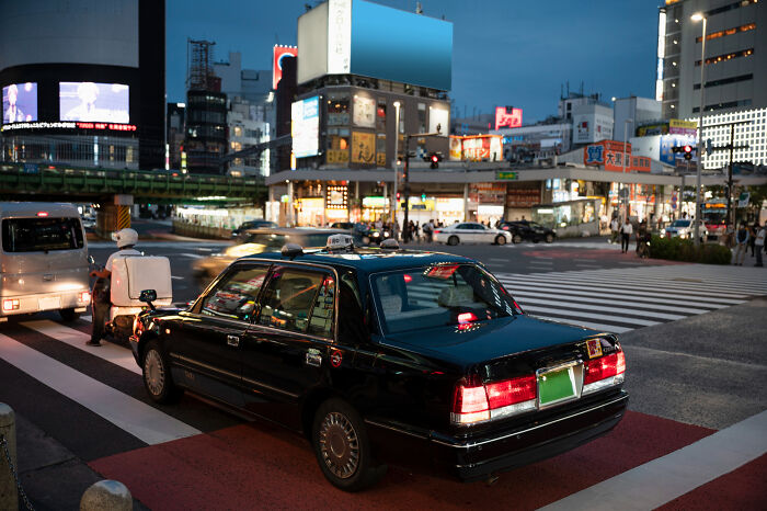 A busy street intersection in a small town at dusk, with cars and buildings, a place with shocking secrets.