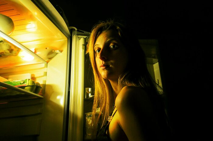 A woman illuminated by the light of an open refrigerator at night. Unsettling stories from small towns.