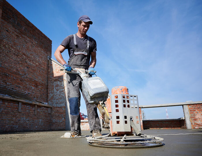 A construction worker using a concrete polisher, showing everyday life in small towns which can hide shocking secrets.