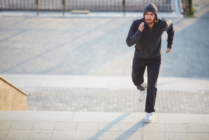 A man running up stairs in a hoodie, a scene that could be from an unsettling story or hide shocking secrets from small towns.