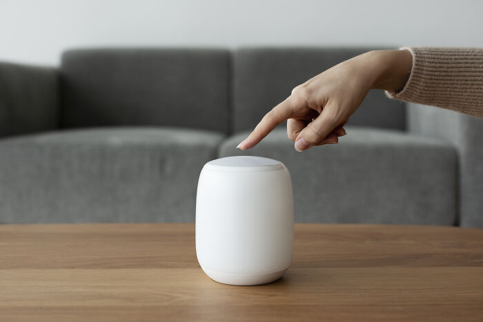 A hand interacting with a smart speaker, illustrating satisfying stories of voice technology.