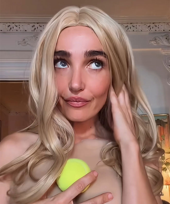 Close-up of Sydney Sweeney wearing a blonde wig and holding a tennis ball, amid comments about her looks sparking uproar. Close-up of Sydney Sweeney wearing a blonde wig and holding a tennis ball, amid comments about her looks sparking uproar.
