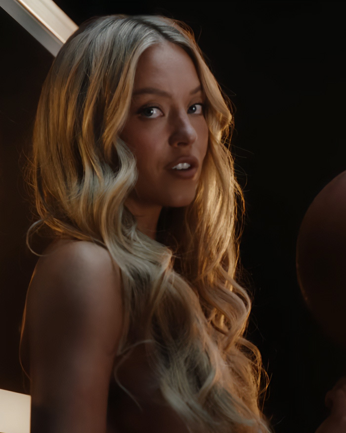 Sydney Sweeney in her controversial betting ad, with a serious expression and long blonde hair looking over her shoulder. Sydney Sweeney in her controversial betting ad, with a serious expression and long blonde hair looking over her shoulder.