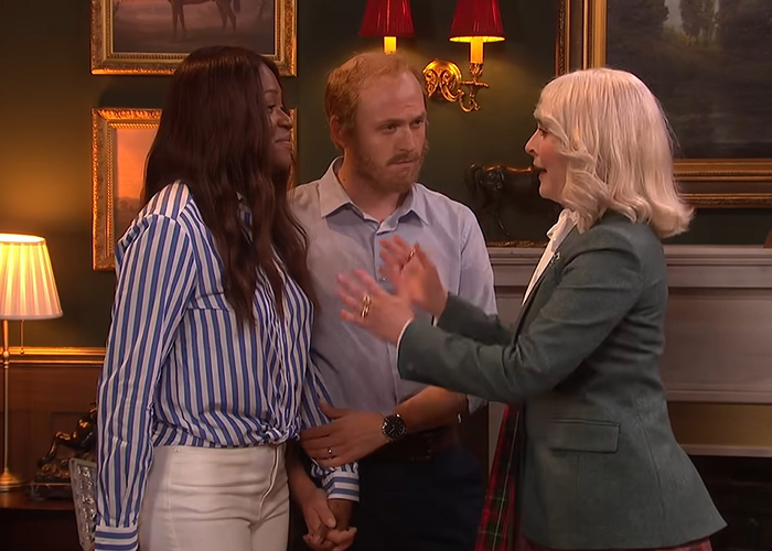 Three actors in an 'SNL UK' skit, with two portraying Meghan Markle and Prince Harry, during their UK return. Three actors in an 'SNL UK' skit, with two portraying Meghan Markle and Prince Harry, during their UK return.