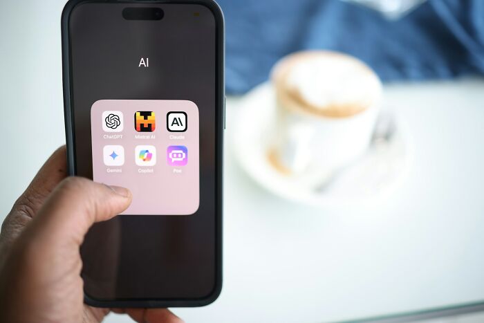 Wildly stupid things people said, a person holding a smartphone showing a folder of AI apps on the screen.