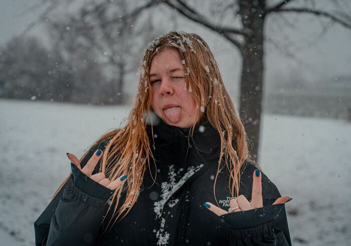 A young woman in a snowy environment with her tongue out, indicating signs of a sociopath.