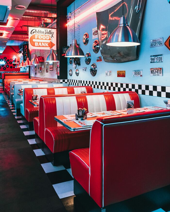 A retro-themed diner with red and white booths and checkered floors, a stereotypical image of the US.