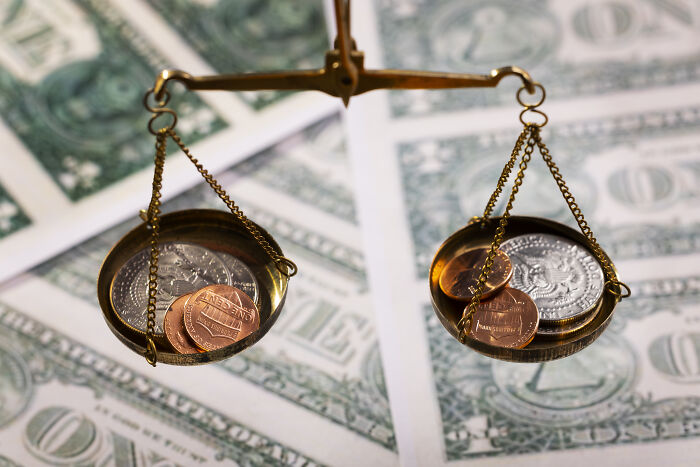 A brass scale balancing coins over dollar bills, showing satisfying stories of financial decisions.