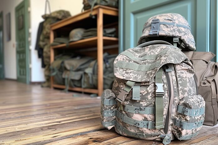 Military backpack and helmet placed indoors on wooden floor